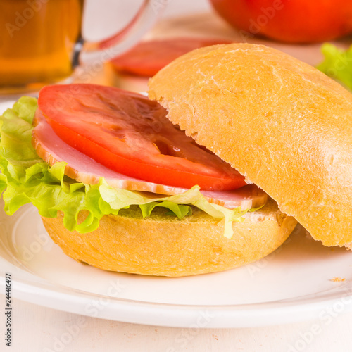 Delicious homemade sandwich with lettuce, ham and tomato close up on a light background