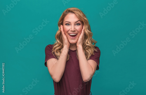 Portrait of blonde surprised emotional girl on blue background.