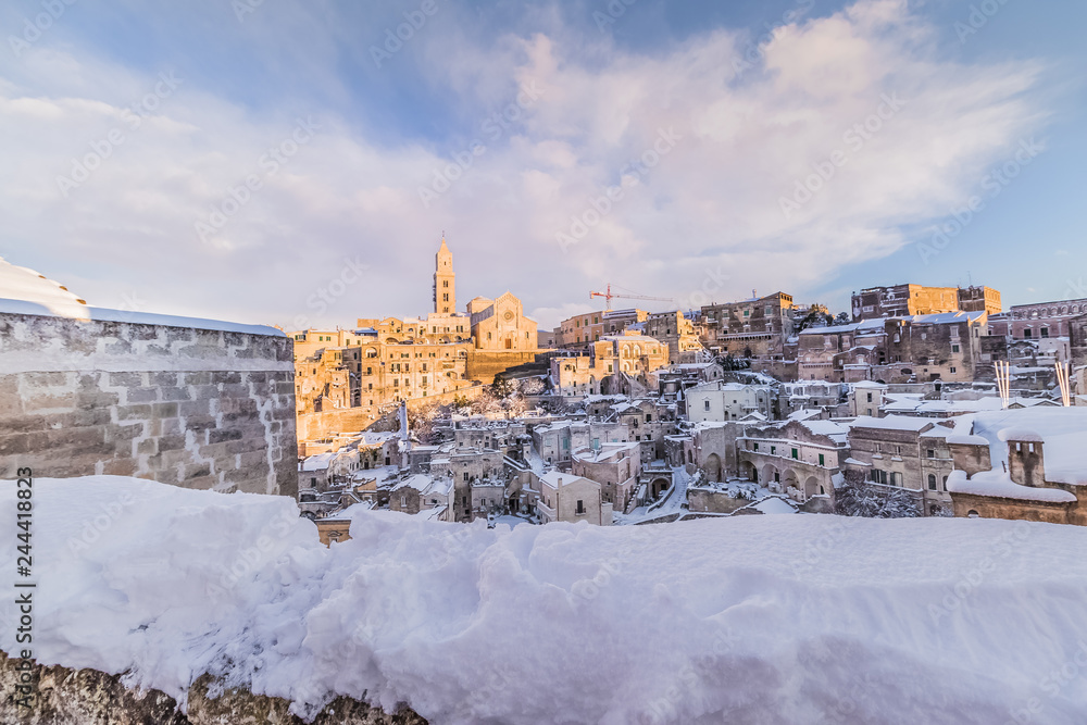 Obraz premium panoramic view of typical stones Sassi di Matera and church of Matera 2019 under blue sky with clouds and snow on the house, concept of travel and christmas holiday,capital of europe culture 2019