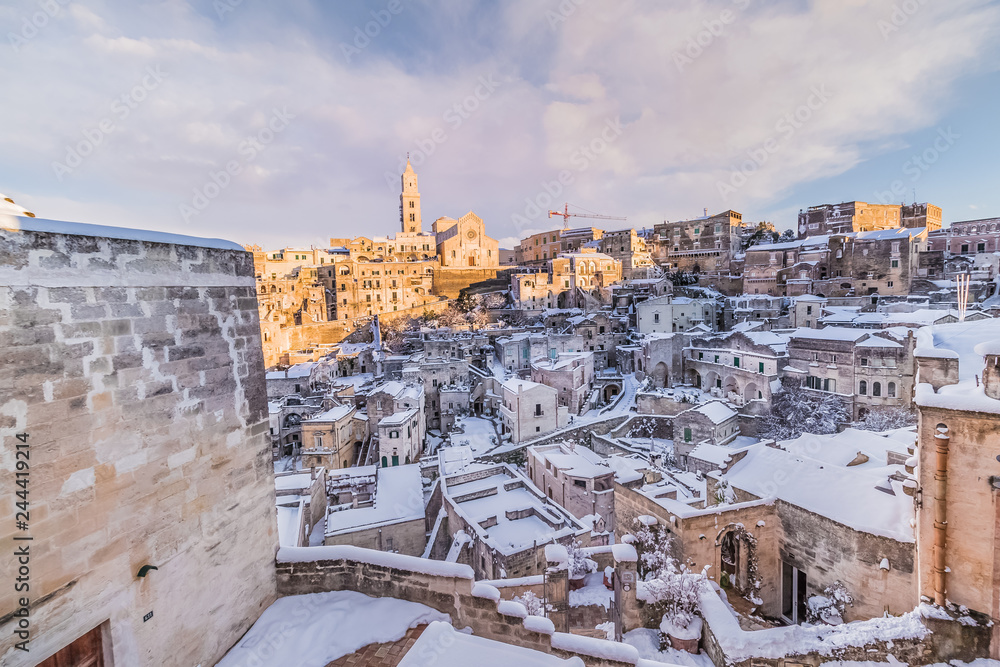panoramic view of typical stones Sassi di Matera and church of Matera 2019 under blue sky with clouds and snow on the house, concept of travel and christmas holiday,capital of europe culture 2019