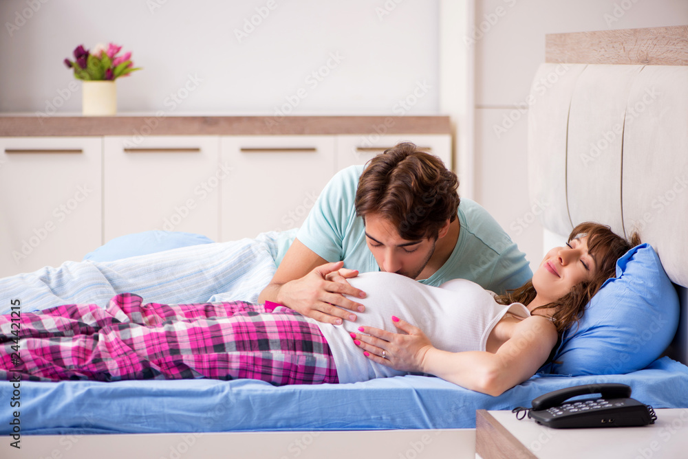 Pregnant woman with husband in the bedroom Pregnant woman with husband in the bedroom
