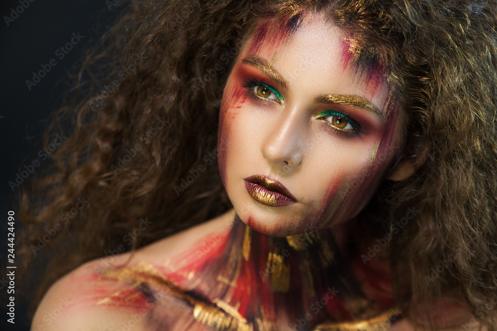 Fototapeta premium beautiful curly girl in a fire makeup and green shadows under the cloak image created by a make-up artist