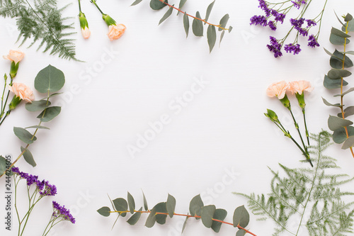 Flowers composition. Paper blank, carnation flowers, eucalyptus branches on pastel  background. Flat lay, top view, copy spaceFlat lay stiil life.