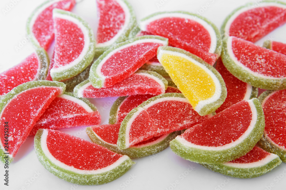 Sweet marmalade in the form of slices of watermelon and lime lies on the white surface of the store counter. Stand out from the crowd Sweet marmalade in the form of slices of watermelon and lime lies on the white surface of the store counter. Stand out from the crowd