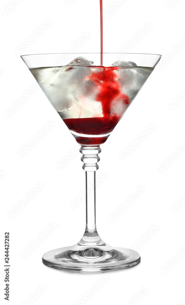 Pouring grenadine into glass of martini cocktail on white background