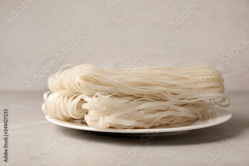 Plate with raw rice noodles on table. Delicious pasta