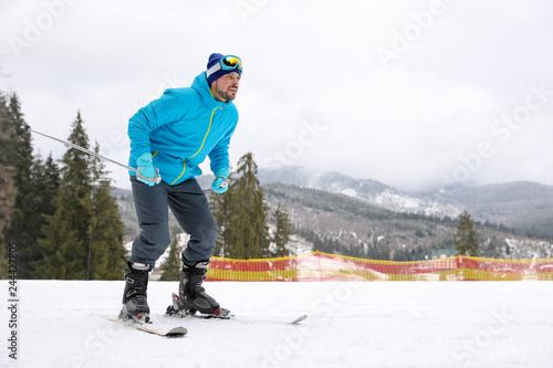Male skier on slope at resort, space for text. Winter vacation
