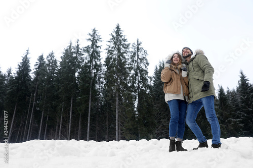 Couple near conifer forest on snowy day  space for text. Winter vacation