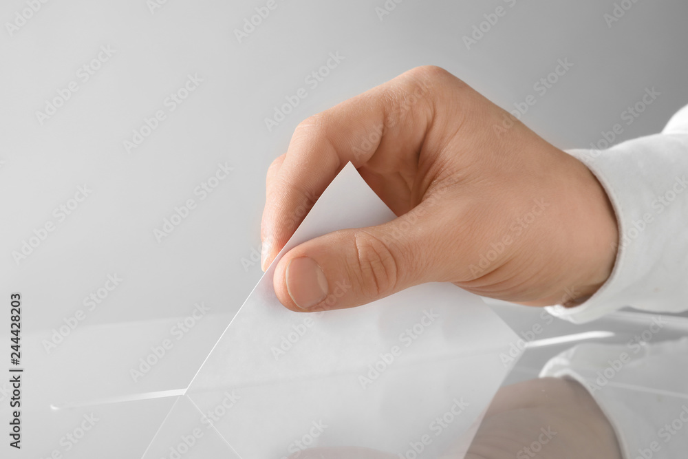 Man putting his vote into ballot box on light background, closeup Man putting his vote into ballot box on light background, closeup