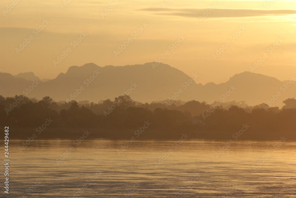 early morning on the river with silhouette mountains and tree