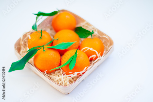 Fototapeta Naklejka Na Ścianę i Meble -  Tangerines with green leaves in a basket 