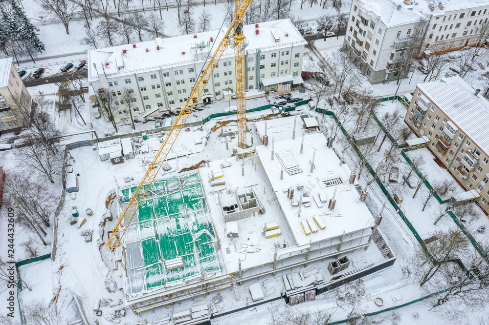 construction site with high yellow tower crane in winter season. aerial top view construction site with high yellow tower crane in winter season. aerial top view