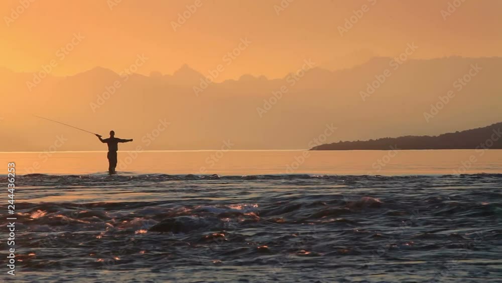 Fisherman fly fishing at sunset at the lake and mountains Fisherman fly fishing at sunset at the lake and mountains