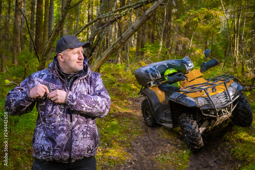 ATV. A man travels through the forest. SUV in the forest. All-terrain vehicle. Kvadro Motorcycle. Mature male traveler. Entertainment in nature. Yellow ATV. Off road travel.