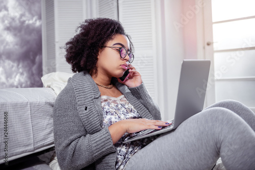 Tired curly woman being freelancer and spending time with laptop