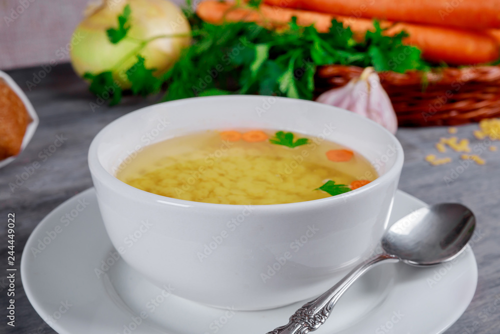 Homemade chicken bouillon in a bowl over vegetable background Homemade chicken bouillon in a bowl over vegetable background