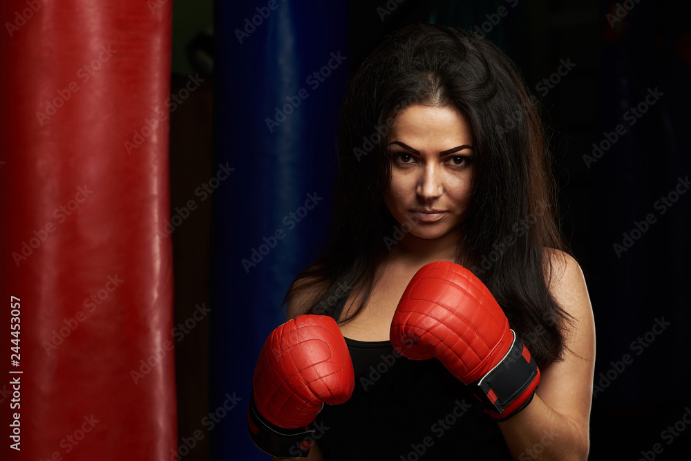 Serious young woman with boxing gloves