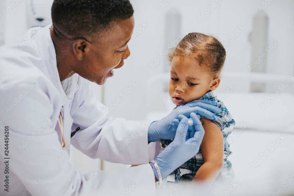 Toddler getting a vaccination by a pediatrician Toddler getting a vaccination by a pediatrician