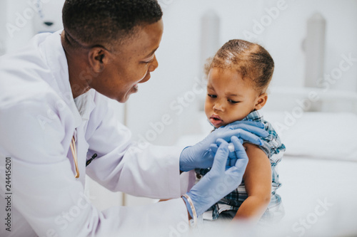 Toddler getting a vaccination by a pediatrician