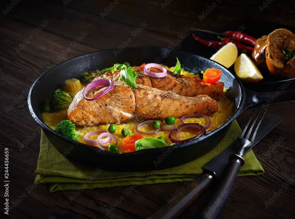 baked salmon steak in a pan on a corn palette with basil on a wooden background. rustic style. baked salmon steak in a pan on a corn palette with basil on a wooden background. rustic style.