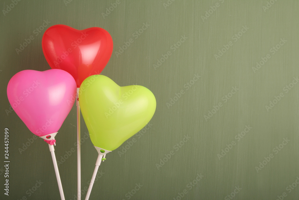Three colorful heart shaped ballons against green chalkboard