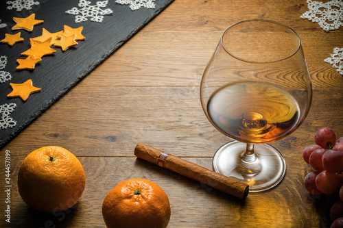 Glass of cognac and cigar with snack on the wood table with stone cutting board. Top view with copy space