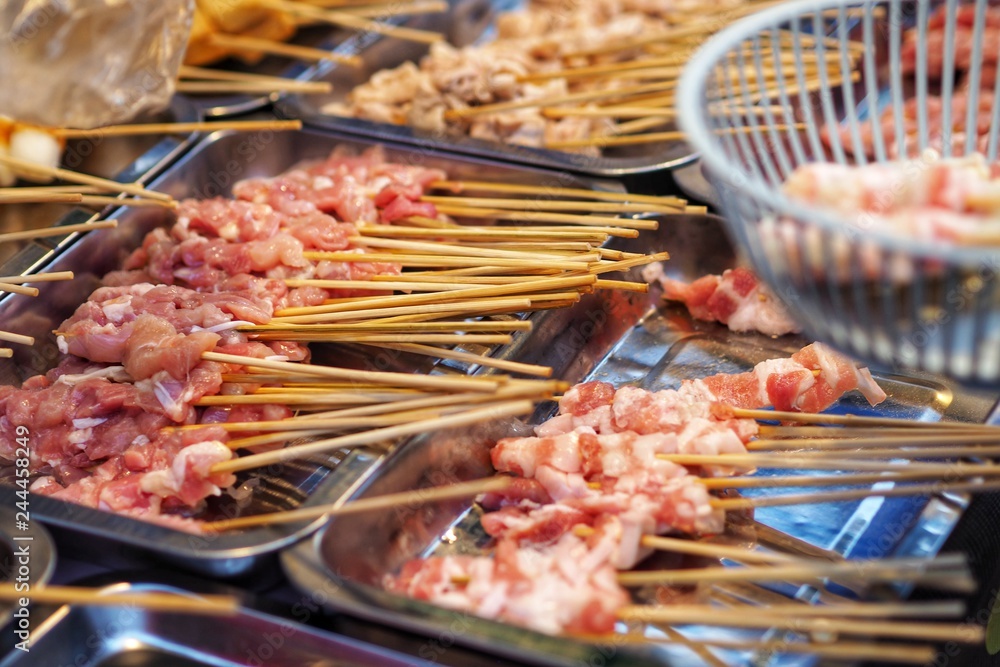 Obraz premium Raw meat beef pork chicken Sausage in wooden stick - street food.