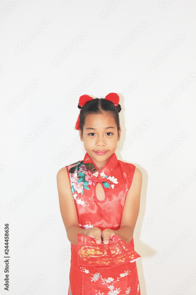 Asian Chinese child happy showing red paper packet gift,Asian girl put on Chinese traditional dress,Chinese new year concept.Symbols of the good luck Chinese New Year. Asian Chinese child happy showing red paper packet gift,Asian girl put on Chinese traditional dress,Chinese new year concept.Symbols of the good luck Chinese New Year.