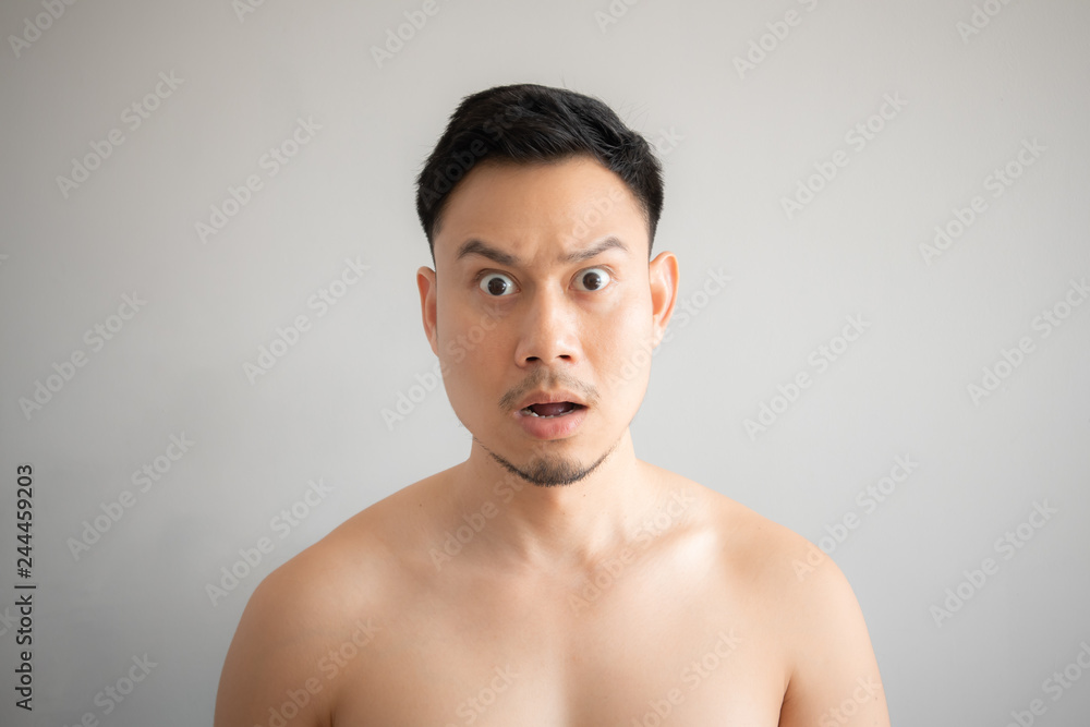 Shock and surprise face of Asian man in topless portrait isolated on gray background. Shock and surprise face of Asian man in topless portrait isolated on gray background.