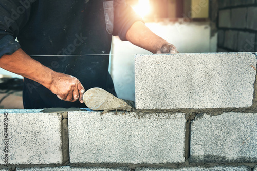 Obraz na płótnie Worker building wall bricks with cement