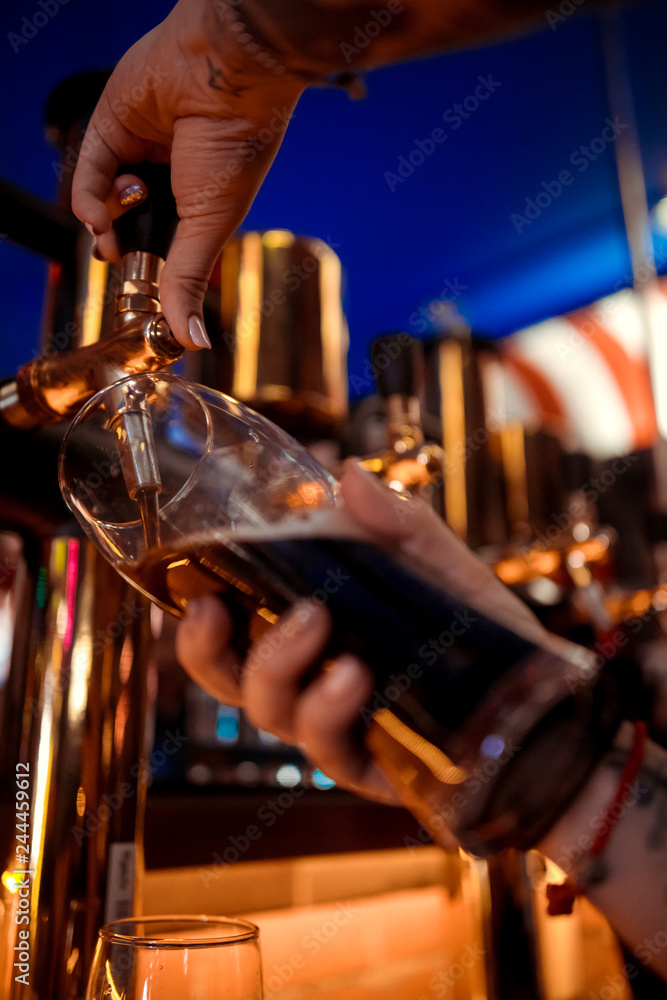 Naklejka premium Hand of bartender pouring a large lager beer in tap.