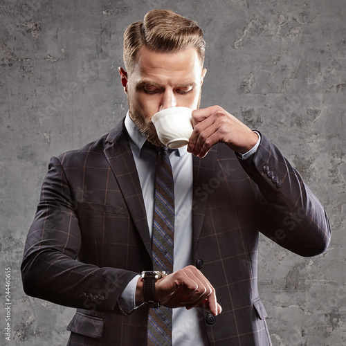 Cuadro en lienzo Handsome man wearing business suit and tie drink coffee or tea and looking at wa