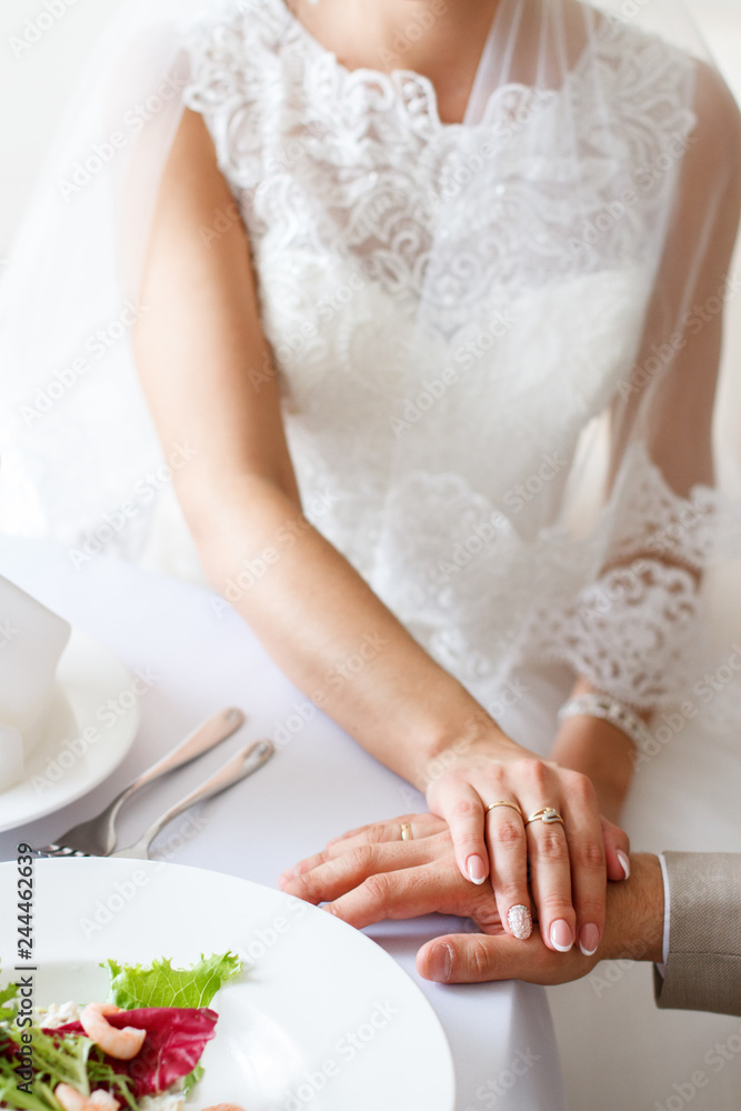 bride and groom hold hands at a table in a restaurant bride and groom hold hands at a table in a restaurant