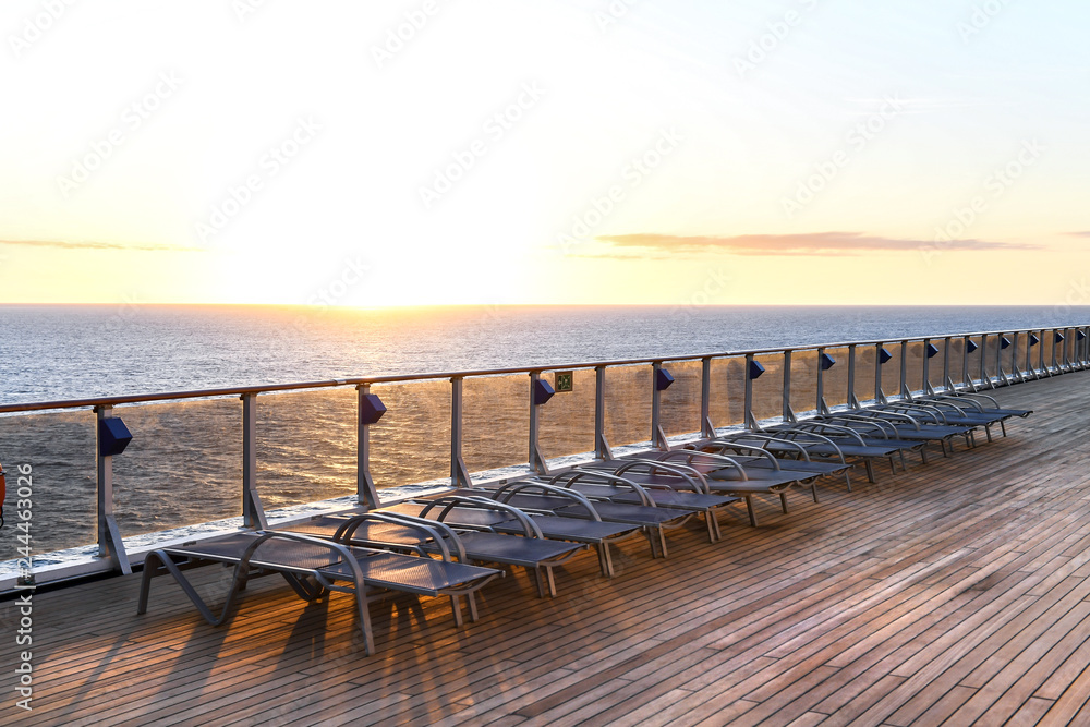 Lounge chairs on a ships deck with the ocean in the background.