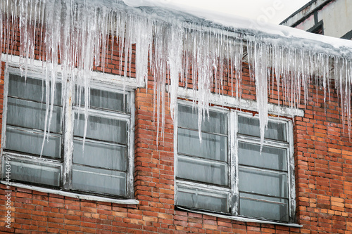 roofs of houses and windows in huge hanging icicles. Winter is harsh in the city © OlegDoroshin
