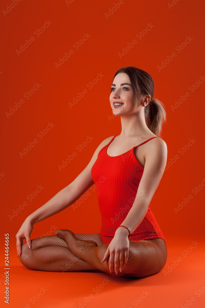 Fototapeta premium young beautiful dancer in orange swimsuit posing on isolated red studio background