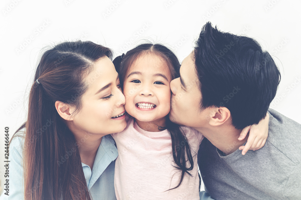 Portrait of attractive asian dad and mom kissing daughter's cheek together close up on isolated white studio background. Parenthood and childhood lifestyle or love and bonding in soft tone concept. Portrait of attractive asian dad and mom kissing daughter's cheek together close up on isolated white studio background. Parenthood and childhood lifestyle or love and bonding in soft tone concept.