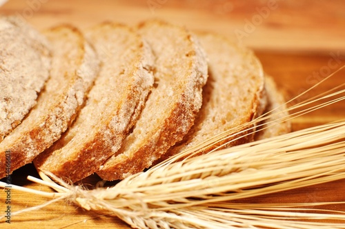 Slices of maroon cereal healthy homemade bread with dried wheat decoration on wooden table background