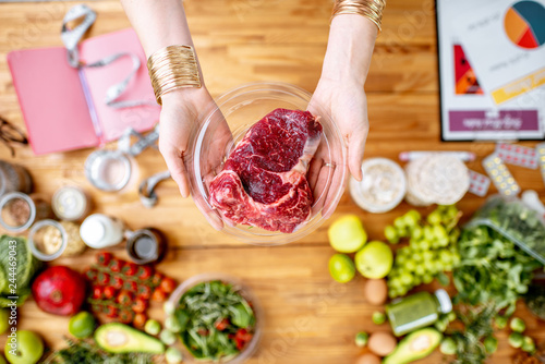 Canvas-taulu Dietitian holding red meat above the table full of various healthy products and