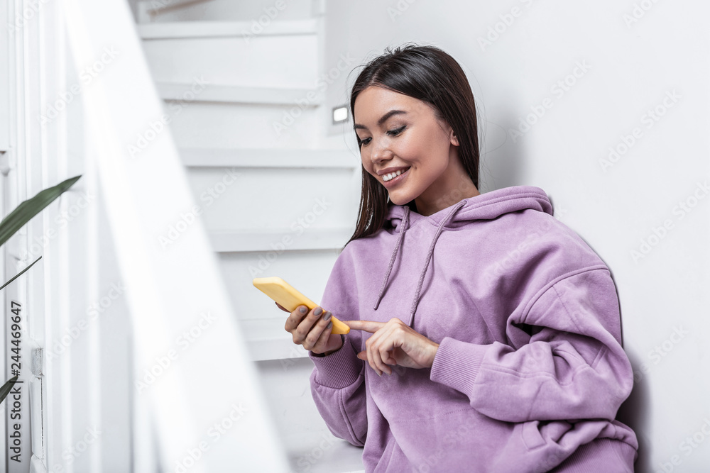 Dark-haired woman holding yellow smartphone while reading message Dark-haired woman holding yellow smartphone while reading message