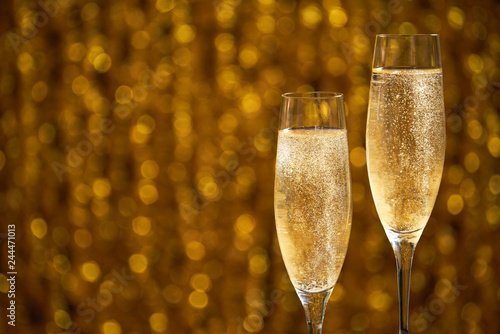 Two glasses of champagne on golden bokeh background