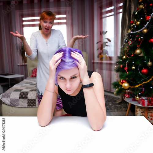 Family problems in the new year - Concept portrait of a mother and daughter with purple hair in a room are fighting