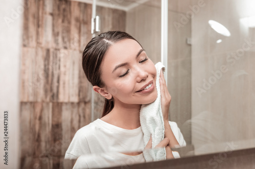 Beautiful woman using white towel after washing her face