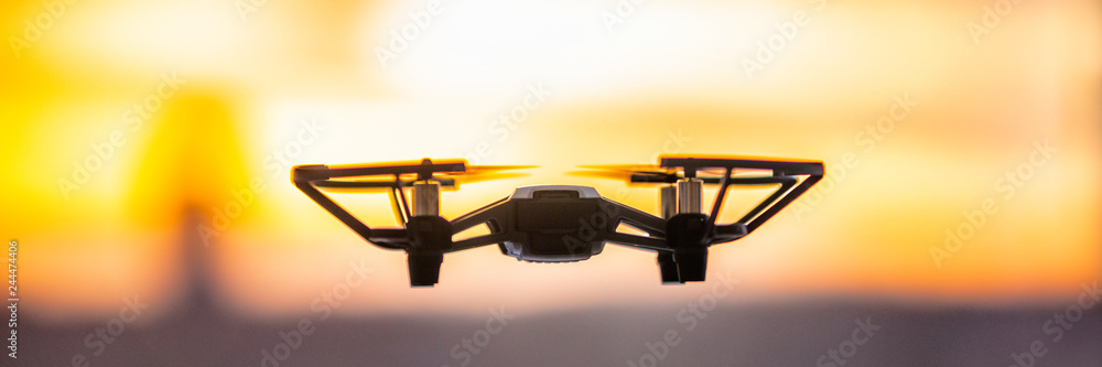 Drone flying outside in sky sunset banner panorama. Closeup of drone quadcopter with security camera outdoor. - obrazy, fototapety, plakaty 