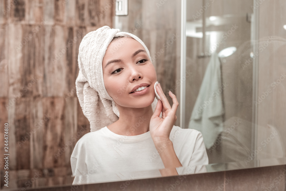 Pleasant young woman using a cotton pad Pleasant young woman using a cotton pad