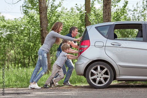 Foto family with children pushing a faulty car