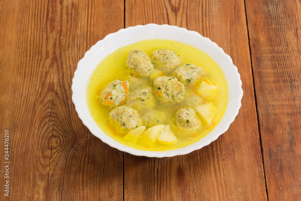 Chicken meatballs soup in white bowl on old rustic table Chicken meatballs soup in white bowl on old rustic table