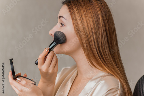 Face powder. Closeup Of Beautiful Female Model Applying powder on a face. Portrait Young Woman. Beauty cosmetics Concept. 