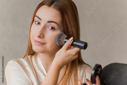 Face powder. Closeup Of Beautiful Female Model Applying powder on a face. Portrait Young Woman. Beauty cosmetics Concept. 