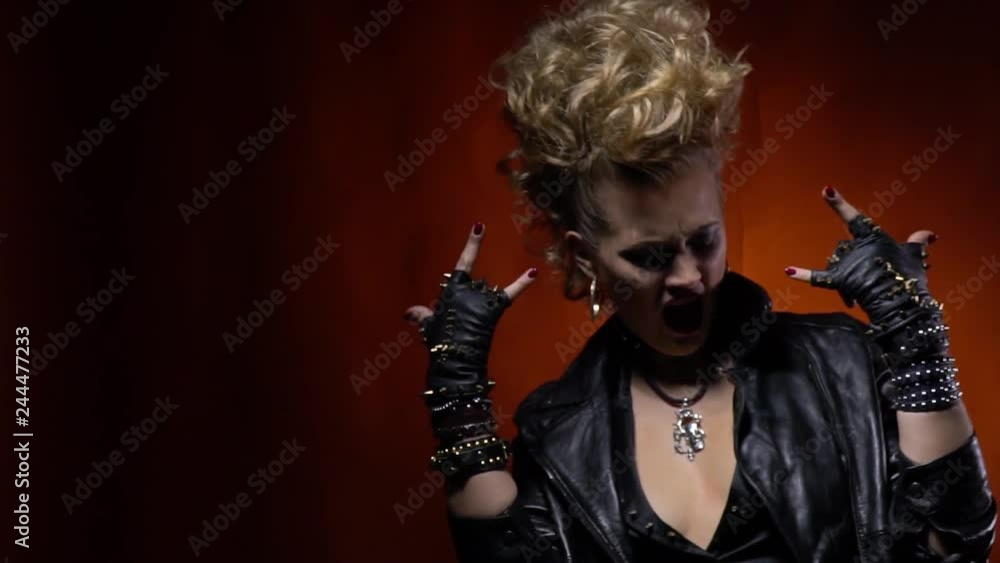Rocker woman in leather jacket shows the sign of the horns Rocker woman in leather jacket shows the sign of the horns